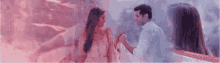 a man and a woman are standing next to each other holding hands in a room .