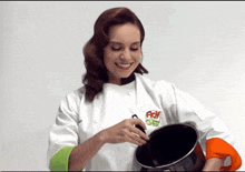 a woman in a chef 's uniform holds a pot and smiles