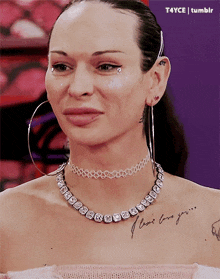 a woman wearing a choker necklace and hoop earrings has a tattoo on her chest that says i love you