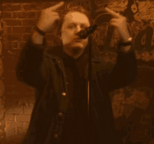 a man singing into a microphone in front of a brick wall that says sleepy head