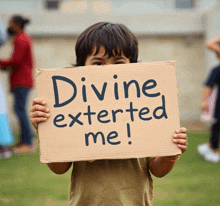a young boy holds a cardboard sign that says divine exterted me