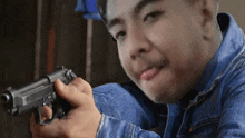 a man in a denim jacket is holding a gun