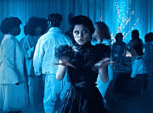 a woman in a black dress stands in front of a crowd