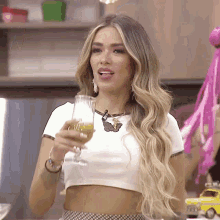 a woman in a white crop top holds a glass of orange juice