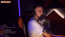 a man wearing headphones is holding a pug dog in his arms in front of a screen that says bastardanchovy
