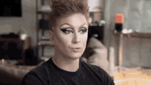 a drag queen is sitting on a couch in a living room wearing makeup .