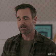 a man with a beard wearing a plaid shirt with netflix written on the bottom