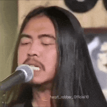 a man with long black hair and a beard singing into a microphone