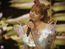 a woman singing into a microphone on a stage with a purple flower in the background