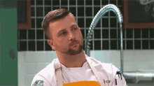 a man with a beard wearing a white chef 's uniform and an apron that says chef on it