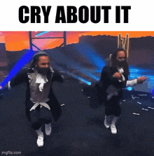 two men are dancing on a stage with the words cry about it above them