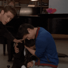 a man in a blue shirt is comforting another man in a black shirt
