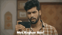 a man in a plaid shirt is taking a picture of himself with the words mrs. raghav rao below him