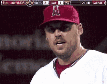 a baseball player wearing a red hat with the letter a on it stands in front of a scoreboard