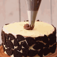 a cake decorated with oreos is being frosted with chocolate frosting