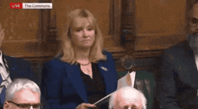 a woman in a blue suit is holding a piece of paper while sitting in a parliament .