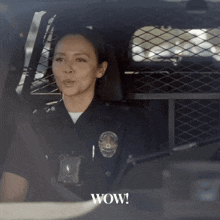 a police officer is sitting in a car with the word wow on the bottom