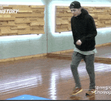 a man in a black hoodie is dancing in front of a wall that says beyond the history