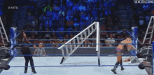 two women are wrestling in a wrestling ring while a referee watches .