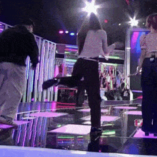 a woman in a white shirt is dancing on a stage with a man in a black shirt