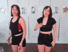 two women are dancing in front of a roar balloon