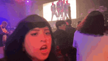 a woman stands in front of a large screen that says ' man '