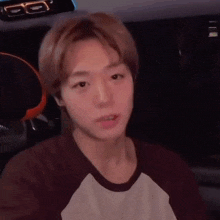 a young man is sitting in a car and looking at the camera .