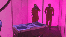 two people in orange jumpsuits are standing in front of a dj mixer