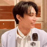 a young man wearing a suit and tie is talking into a swag microphone