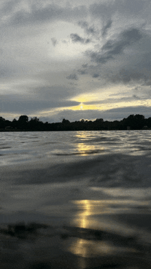 a sunset over a lake with trees in the distance