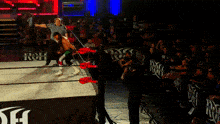 a referee stands in a wrestling ring with a banner that says ' rh ' on it
