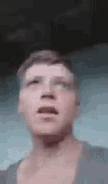 a close up of a man 's face with his mouth open and a blurry background .