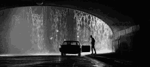 a man is standing next to a car in a tunnel with the door open .