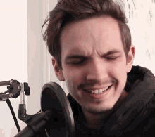 a man is smiling in front of a microphone and making a funny face