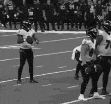 a group of football players are standing on a field holding a ball .