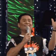 a man wearing a rugrats shirt is holding a microphone