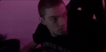 a man is sitting in a chair in front of a computer screen with a pink background .