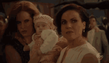 a woman is holding a baby in her arms while two other women look on .