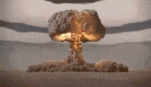 a nuclear explosion in the middle of a desert with mountains in the background .