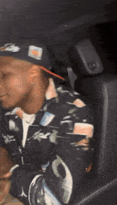 a man is sitting in the back seat of a car wearing a hat and a jacket .