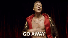a shirtless man with a gold chain around his neck is standing in front of a red curtain and says go away .