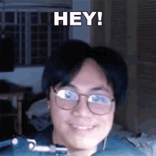 a man wearing glasses is smiling with the words hey in the background