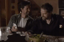 a group of men are sitting at a table eating food .