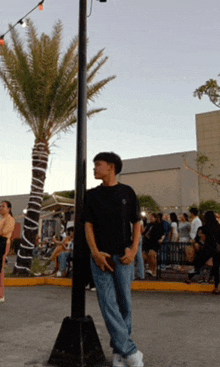 a man in a black shirt is standing next to a pole
