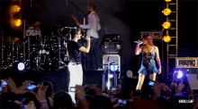 a man singing into a microphone in front of a drum set with rbd on it