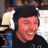 a man wearing headphones is smiling in front of a picture of a blue bear .