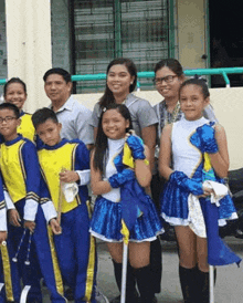 a group of children in marching uniforms are posing for a picture with their teacher .