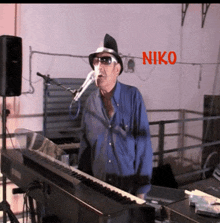 a man singing into a microphone with niko written in red behind him