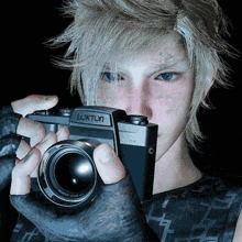 a young man is holding a luxton camera in his hands