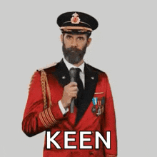 a man in a red suit and hat is pointing at the camera with the word keen .